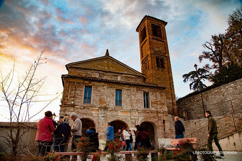 Visitatori davanti a una chiesa del borgo al tramonto